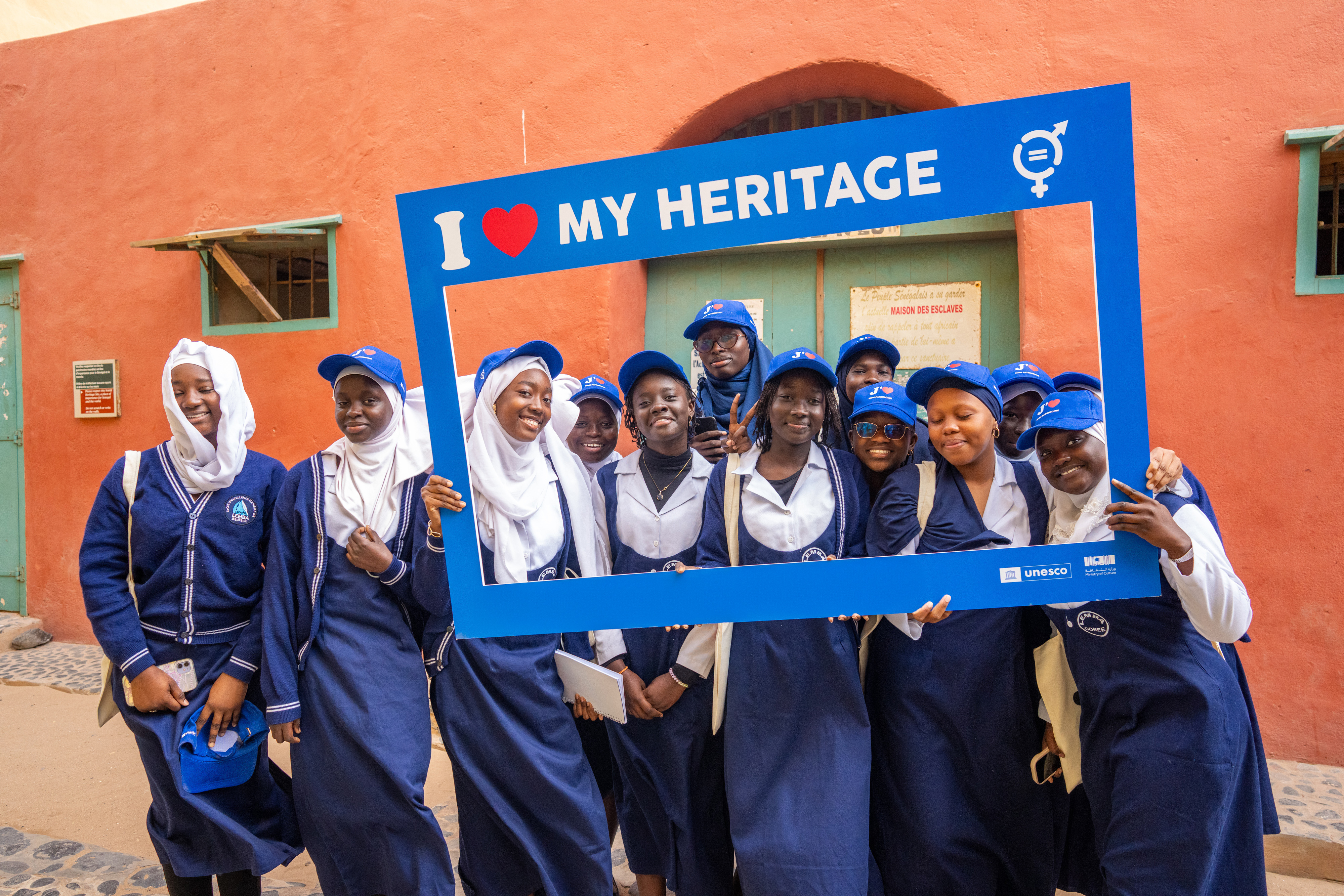 African youth holding an 'I love my heritage' frame at a UNESCO heritage site in Rwanda, celebrating youth-led cultural conservation and pride