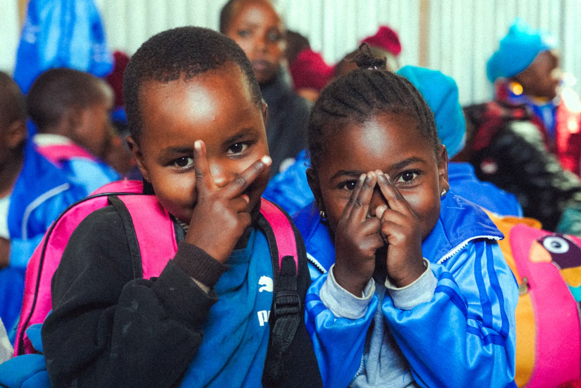 Two young students in school tracksuits smiling and playing during an arts education session in South Africa