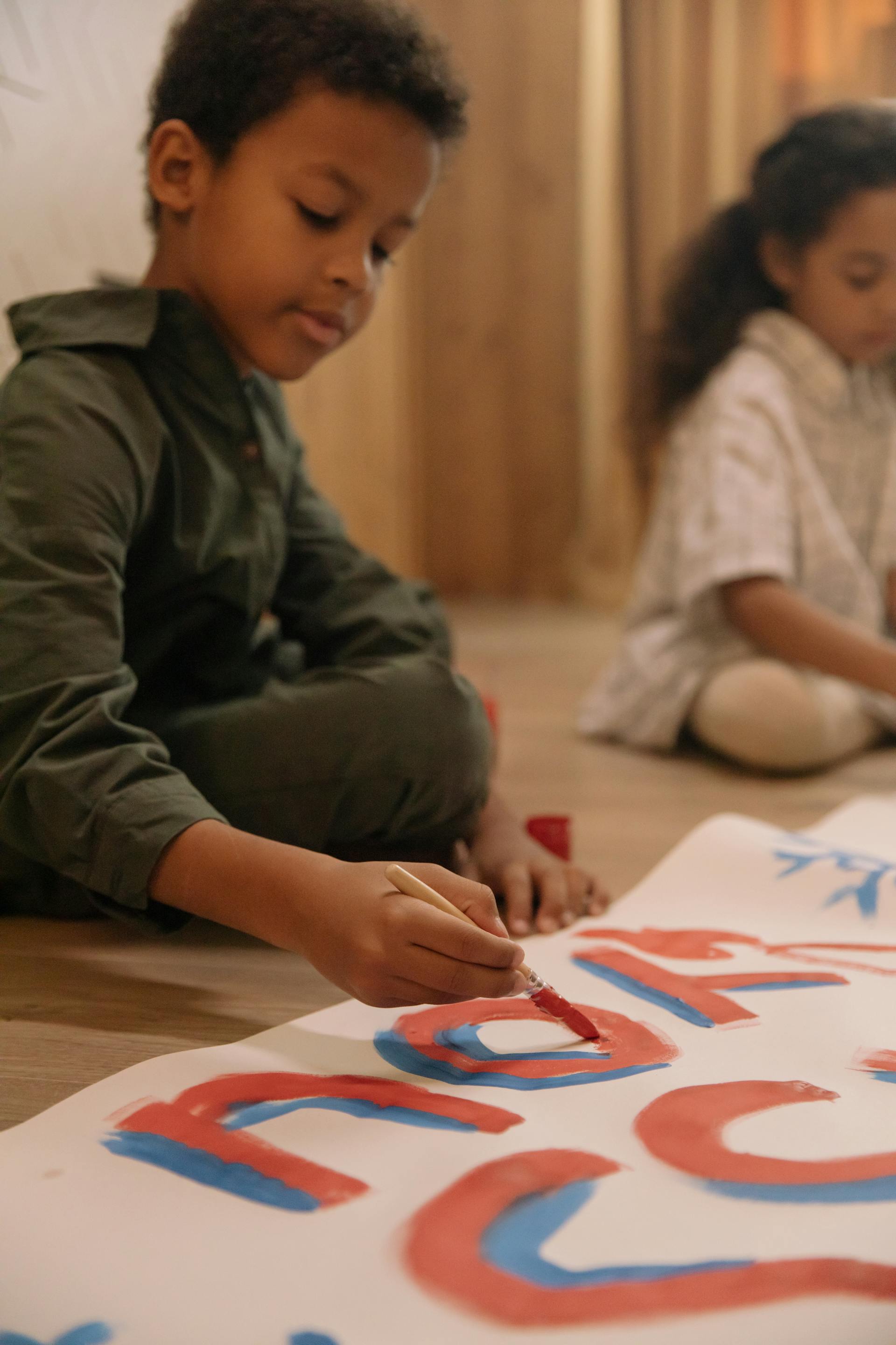 A young child paints colourful lettering on a large sheet during an arts and culture class in Eswatini